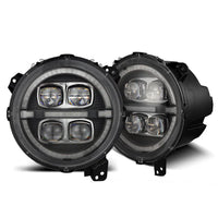 Two round LED headlights from the AlphaRex USA NOVA-Series LED Projector Headlights - Black - 2018-2023 Jeep Wrangler JL/Gladiator JT (SKU: 880868), designed for Jeep Gladiator JT and Jeep Wrangler JL, are shown. The lights feature a black housing and a clear lens, with intricate design details for optimal light distribution. Both headlights are positioned side by side on a white background.