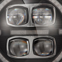 Close-up of a sleek, modern car headlight featuring four circular lens compartments arranged in a square pattern. The AlphaRex NOVA-Series LED Projector Headlights for the 2018-2023 Jeep Wrangler JL/Gladiator JT (SKU: 880868) by AlphaRex USA have a glossy black finish with intricate detailing and a clear lens cover. Light reflections are visible on the surface.