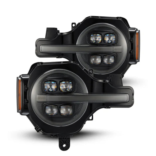 Two black, round LED headlights, resembling those of the Ford Bronco, are displayed one after the other. Each AlphaRex USA NOVA-Series LED Projector Headlight - Alpha-Black (SKU: 880259) for the 2021-2023 Ford Bronco/Raptor features two primary circular lights with smaller lights arranged horizontally within a protective casing. The headlights also include side markers on the left edge.