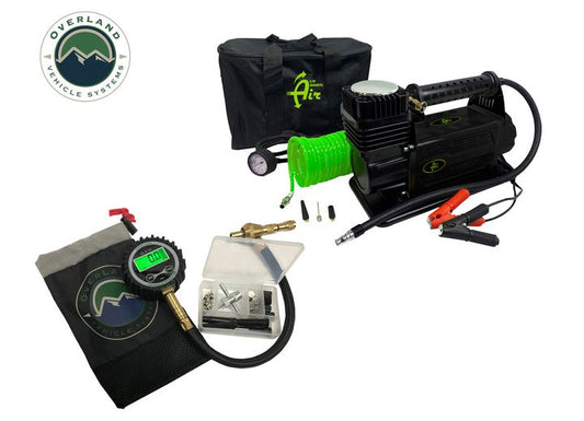 The image features the AIR COMPRESSOR SYSTEM 5.6 CFM AND DIGITAL TIRE DEFLATOR COMBO KIT from Overland Vehicle Systems. The kit comprises a black air compressor, a green coiled hose, a digital tire deflator and pressure gauge, various fittings, and a carrying case. The Overland Vehicle Systems logo is visible in the top left corner.