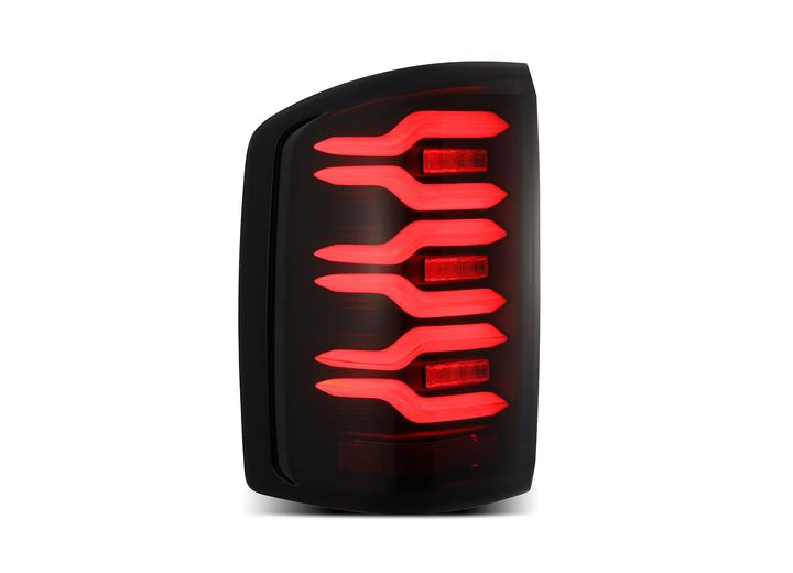 Close-up of the AlphaRex USA 14-18 SIERRA 1500/2500/3500HD LUXX LED tail lights in Alpha-Black with activation light and sequential signal. The modern red LEDs exhibit a sleek, curved design, featuring a series of stacked, horizontal segments encased in a dark, glossy finish that creates a distinct, futuristic appearance.