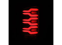 Close-up of an AlphaRex USA 14-18 SIERRA 1500/2500/3500HD LUXX LED tail light in the dark, showcasing five red light bars. The bars vary in length and are arranged in a layered, horizontal design that creates a unique and modern look. The completely black background accentuates the illuminated light bars.