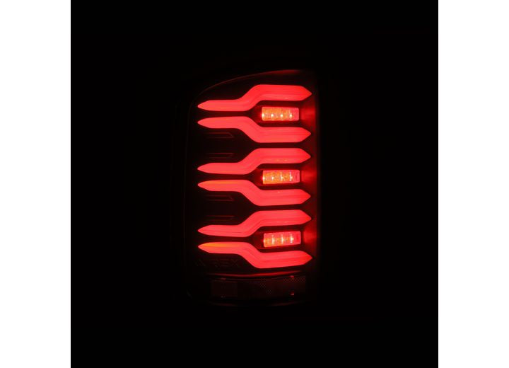 Close-up of a 14-18 Sierra 1500/2500/3500HD LUXX LED tail light from AlphaRex USA in the dark, featuring four curved, horizontal red light strips glowing brightly. The segmented design of these lights delivers a modern, distinct look that starkly contrasts against the black background.