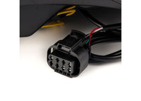 Close-up image of a rectangular AlphaRex USA electrical connector with multiple metal contacts, attached to a black cable. The background is white, featuring part of a black object and yellow wires. This component is from the 14-18 SIERRA 1500/2500/3500HD LUXX LED Tail Lights Alpha-Black w/ Activation Light & Seq Signal.