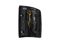 A product from AlphaRex USA, the 14-18 Sierra 1500/2500/3500HD LUXX LED Tail Lights in Alpha-Black with activation light and sequential signal, features a rectangular black plastic housing with internal wires including yellow and black ones connected to a central module. This electronic component includes several mounting points and screws for secure installation.