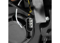 A close-up view of the three-pronged electrical connector reveals the black and yellow wires visibly attached to it, set against a background displaying various components of what appears to be an AlphaRex USA product: the 21-23 F150 LUXX LED PROJECTOR HEADLIGHTS ALPHA-BLACK W/ ACT LIGHT & SEQ SIGNAL.