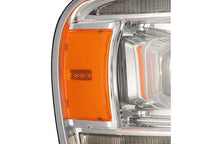 Close-up of the AlphaRex USA RAM 1500/2500/3500 2002-2005/2003-2005 Nova-Series LED Projector Headlight - Alpha Black, featuring a prominent orange reflector on the side. The clear lens and surrounding chrome detailing showcase the intricate design, ensuring enhanced visibility.