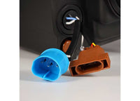 Close-up of blue and brown electrical connectors with wires attached, placed on a grey surface. These connectors appear to be part of an automotive or electronic component, possibly for linking AlphaRex USA's RAM 1500/2500/3500 2002-2005/2003-2005 Nova-Series LED Projector Headlights in Alpha Black for enhanced visibility. The background is slightly blurred.