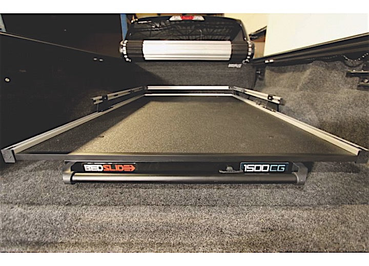 A BEDSLIDE 1500 CONTRACTOR 78IN X 48IN from Bedslide is installed in the truck bed. The sliding platform is partially extended, revealing a flat, carpeted surface and side metal rails. The truck's interior is visible, emphasizing a clean and organized setup.