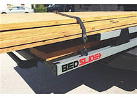 A close-up of a Bedslide system attached to the back of a vehicle, extended with a load of wooden planks secured using the 4-Piece Heavy-Duty D-Ring Tie-Down Kit for Secure Cargo Transportation. The Bedslide logo is visible, showcasing the ease and secure cargo transportation from the truck bed.