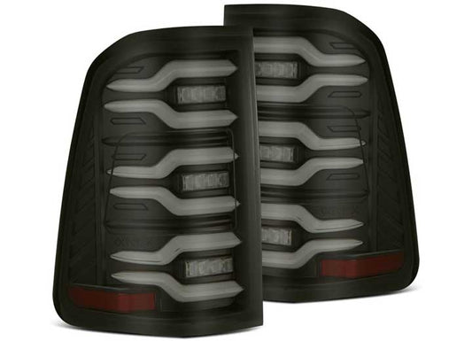 A pair of AlphaRex USA RAM LUXX LED Tail Lights Black with Sequential Signal for 2019-2022 Models designed for a vehicle. They feature a layered LED pattern with horizontal slats, integrated brake and reverse light sections, and a sequential signal feature. The dark-tinted casing with a black finish gives the lights a sleek and modern appearance.