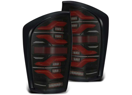 A pair of the AlphaRex USA 16-23 Tacoma LUXX-Series LED tail lights in black and red, featuring a sleek and modern design with activation light and sequential signal red. These aftermarket tail lights boast black housing with red and white sections in a bold, angular pattern, positioned side by side against a white background.