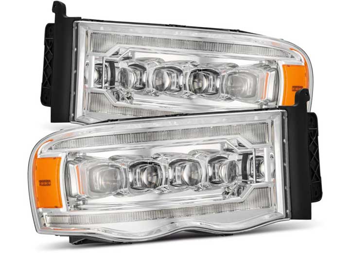 The AlphaRex USA Nova-Series LED Projector Headlights for RAM 1500/2500/3500 (2002-2005/2003-2005) in Alpha Black feature a modern design with clear lenses and intricate internal detailing. These headlights are equipped with multiple LED bulbs to enhance visibility, and their outer edges include amber reflectors. They are designed for easy installation on either side of your vehicle's front end.