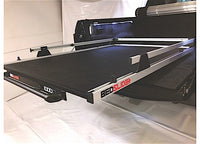 A close-up view of a truck bed with the BEDSLIDE 1000 CLASSIC 58IN X 39IN installed. This sliding truck bed platform from Bedslide is an extendable setup that allows easy access to cargo by pulling the bed out towards the end of the truck. The design is sleek, featuring a black base and silver rails branded with "BedSlide.