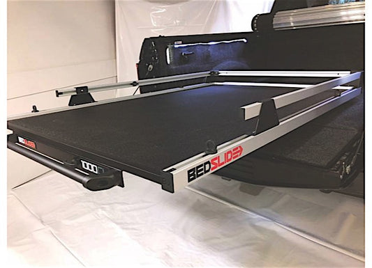 A black truck bed with an extended Bedslide BEDSLIDE 1000 CLASSIC 95IN X 48IN cargo management system installed, featuring a sliding bed platform with aluminum rails. The image shows the truck bed accessory partially pulled out for easy access to the truck bed contents. The background is a plain white surface.