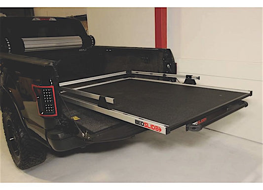 A black pickup truck with its tailgate down, showcasing a Bedslide BEDSLIDE 1500 CONTRACTOR 78IN X 48IN cargo management system. The sliding platform is extended out from the truck bed, revealing a sturdy, flat surface designed for easy loading and unloading of cargo.