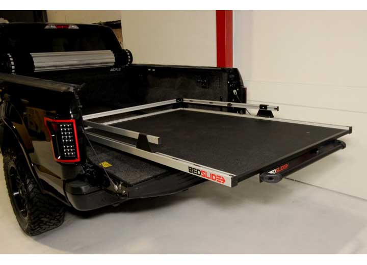 A black pickup truck with an extended BEDSLIDE 1500 Contractor Sliding Truck Bed Organizer - 63" x 47 by Bedslide, featuring a metal platform designed for easy loading and unloading of cargo. The platform is pulled out from the truck bed, showcasing its functionality and enhancing truck bed organization.