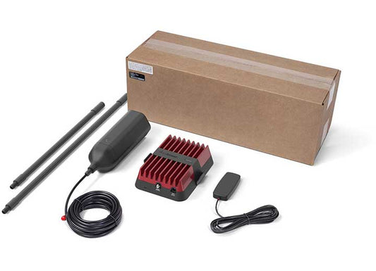 A boxed weBoost Drive Reach OTR Fleet Signal Booster Kit includes an antenna, modem, power cable, and two mounting brackets. The antenna is large and cylindrical, the modem features a red heatsink, and the peripherals are neatly coiled or placed. Designed for fleet vehicles, this setup appears ready for installation.